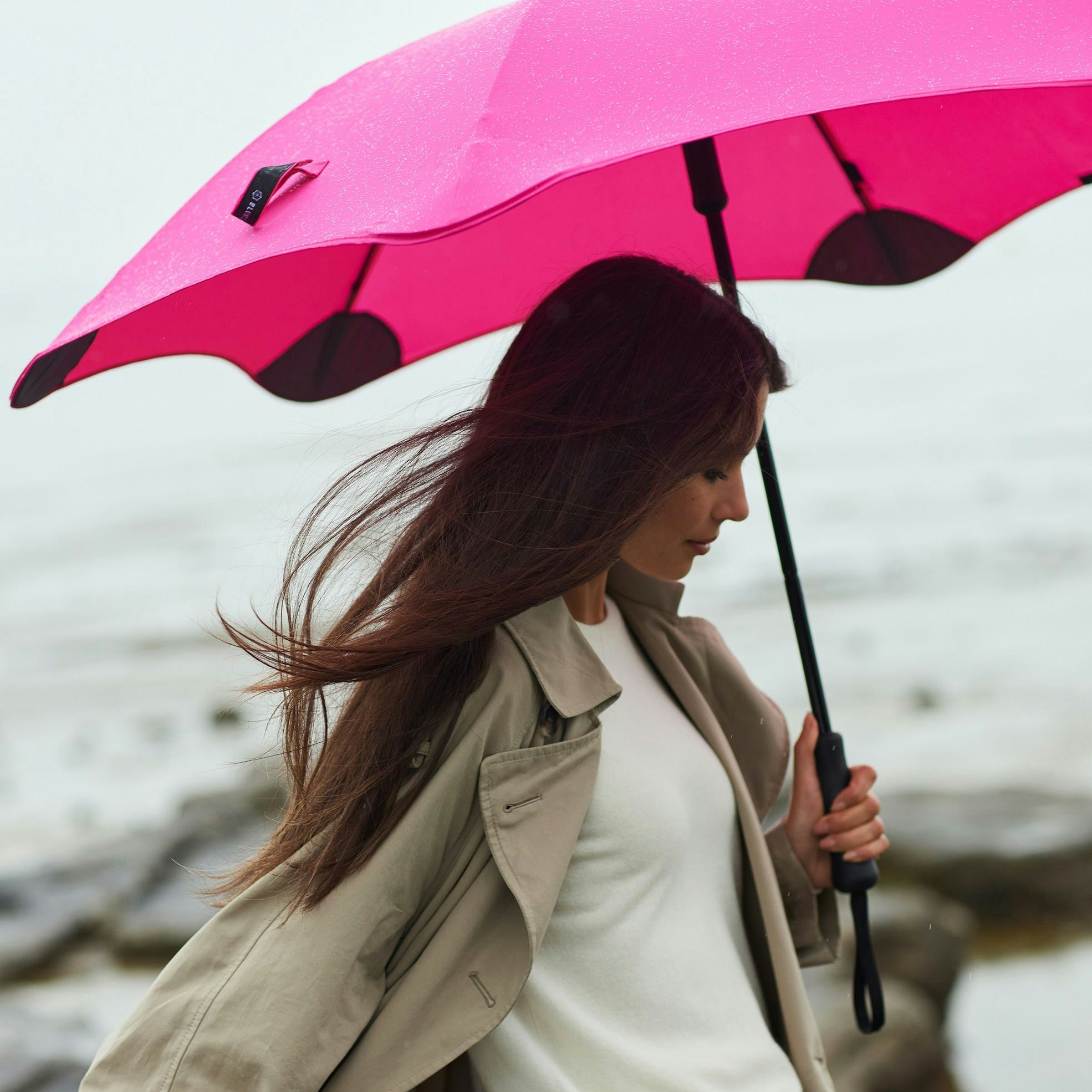 Woman holding a Blunt Metro Umbrella colour Pink on a wet day