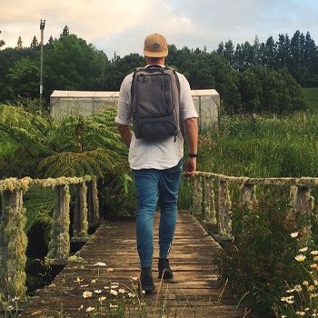 Man walking along a bridge with his nomad backpack on in the countryside