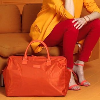 Women in orange posing with orange lipault bag