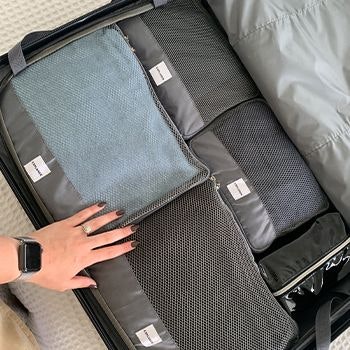 Grey explorer packing cubes packed into a suitcase