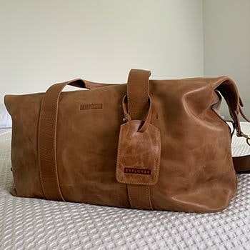 Explorer Weekender Leather Duffle Tan placed on a bed