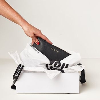 A saben wallet being unwrapped and unboxed, with a hand reaching for it