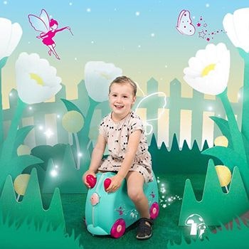 Little girl on her Una the Unicorn Trunki surrounded by a cartoon garden