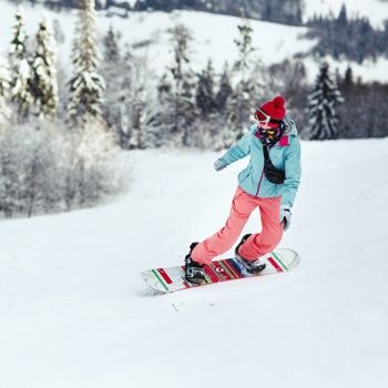 Woman snowboarding down a snowy mountain