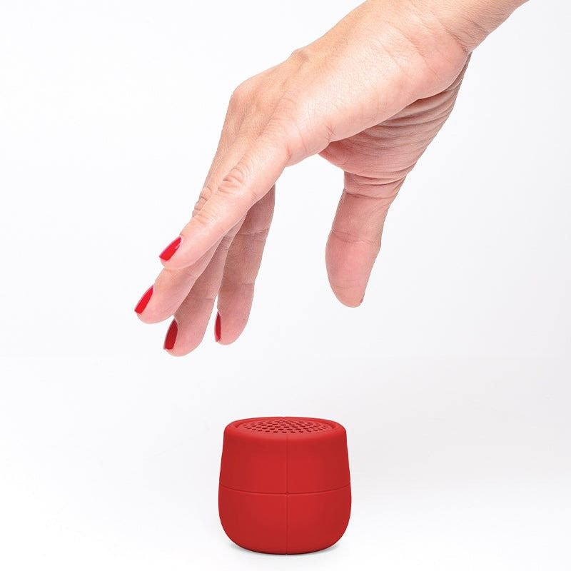 Red Lexon Mino X Floating Bluetooth Speaker with hand reaching for it