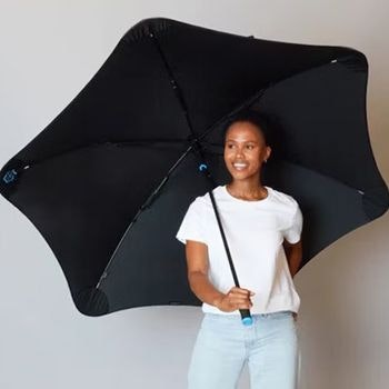 Woman smiling and holding a Blunt Sports Umbrella in black