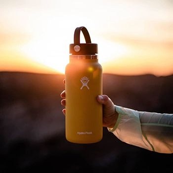 Yellow Hydro Flask bottle held up to the sun at sunset